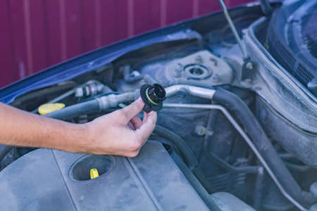 Mechanic checking and fixing a oil filler capof a broken car in car on the road.