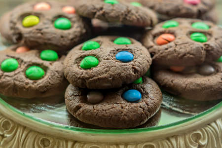 Sweet chocolate cookies with colorful candies on a display, selective focus