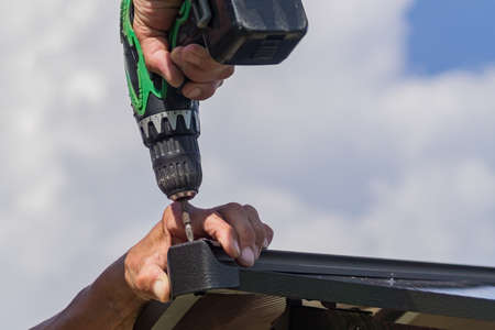 electric screwdriver in males hand. Worker with a hand tool assembling metal constructionの写真素材
