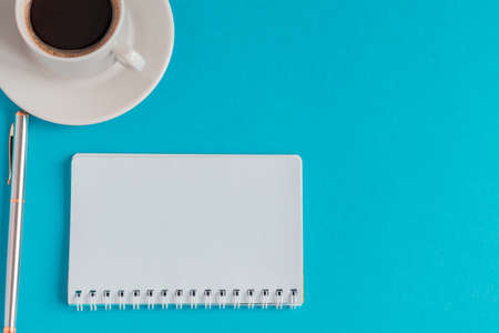 cup of black coffee with notebook and pen on light blue background. business concept with copy space