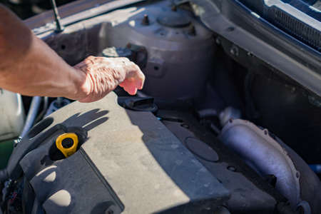 Mechanic checking and fixing a oil filler capof a broken car in car on the road.