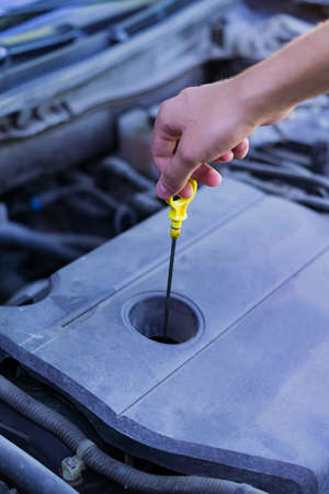 Mechanic checking and fixing a dipstick to check the oil level in car engineの写真素材