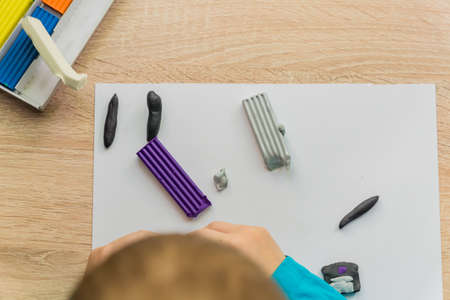 little boy playing with colorful modeling clay. Creative kid molding at home.