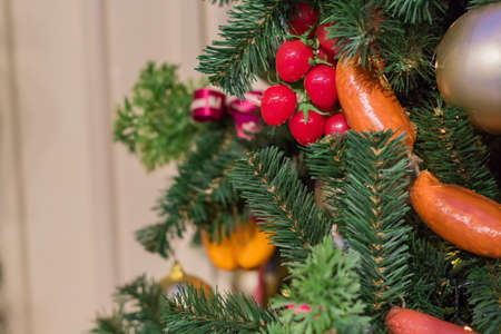 Christmas and New Year holidays background. Christmas tree decorated with artificial sausagws, tomatoes and ballsの写真素材