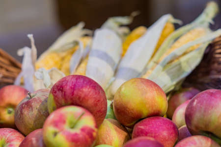 red ripe apples and corn cobs in a basket at the farmer's market