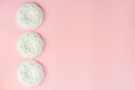 top view of homemade white air meringues on pink background