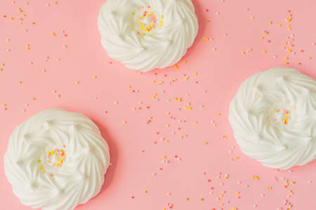 top view of homemade white air meringues and confectionery decorations on pink backgroundの写真素材