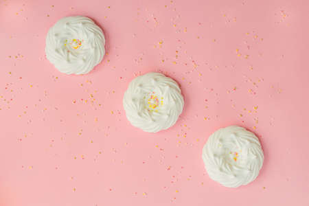 top view of homemade white air meringues and confectionery decorations on pink backgroundの写真素材