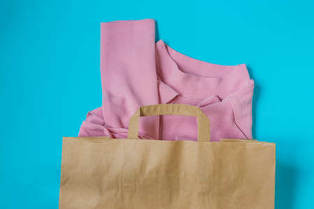 Pink woman blouse in paper craft package on blue background. Clothing sale and black friday concept. Top view.の写真素材