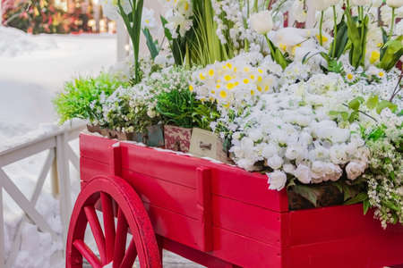 red wooden wheelbarrow with wooden boxes full of blooming artificial flowers. Street and garden decoration.の写真素材