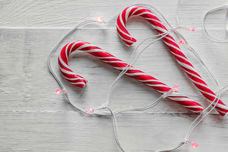 two candy canes and electric garland on wooden background. Traditional Christmas candies.の写真素材