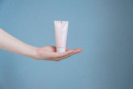 woman holding moisturizing cream. Pink tube in female's handsの写真素材