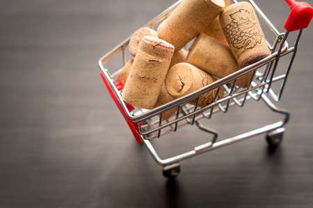 shopping cart full of used vine corks, concept on black wooden backgroundの写真素材