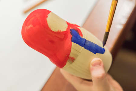 Kid decorating wooden doll toy (russian matrioshka) at the workshopの写真素材