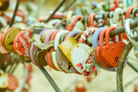 Plenty of multicolored love padlocks on metal railing of the bridge. selective focus, toned.