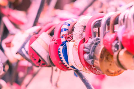 Plenty of multicolored love padlocks on metal railing of the bridge. selective focus, toned.の写真素材