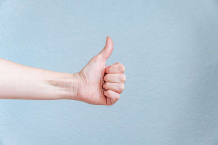 Female hand showing thumb up on blue background. Satisfaction concept.の写真素材