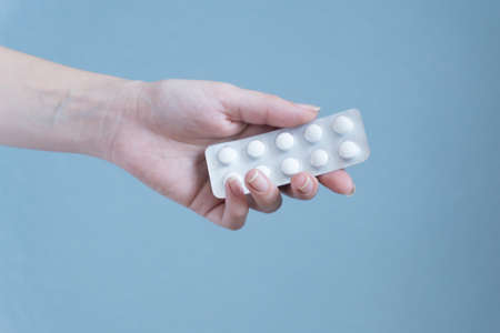 Woman hand holding blister of pills on blue background.の写真素材