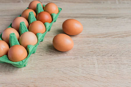 close up of raw brown chicken eggs in egg carton box on wooden table.の写真素材