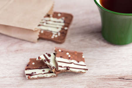 Green cup of americano and milk chocolate bar on wooden backgroundの写真素材