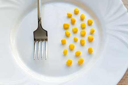 Close up of sweet corn i and steel fork on white plate.の写真素材