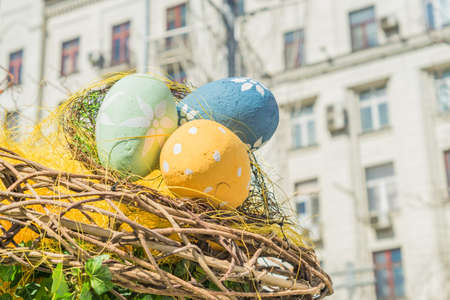 wooden nest with three multicolored eggs. Painted easter decoration outdoors