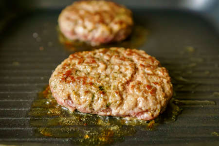 cooking meat burgers with spices on grill at home. Close up, selective focusの写真素材