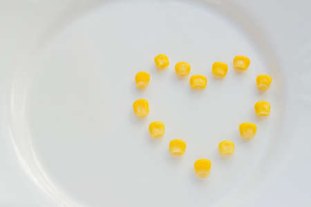 Close up of sweet corn in shape of heart on white plate. Copy space for your text