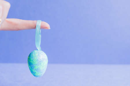Female hand holding blue sparkling easter egg.の写真素材