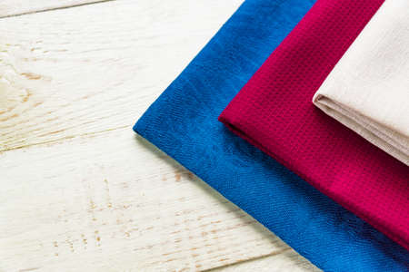 close up of cloth napkins of beige, blue and burgundy colors on rustic white wooden table. Shallow...