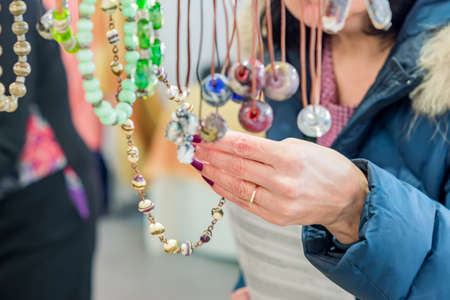 brunette wooman in blue fur coat choosing necklace on flea market. Shopping backgroundの写真素材