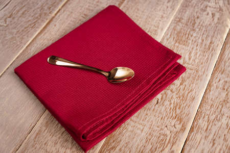 Top view of cloth napkin of beige color and served tea spoon on wooden table.の写真素材
