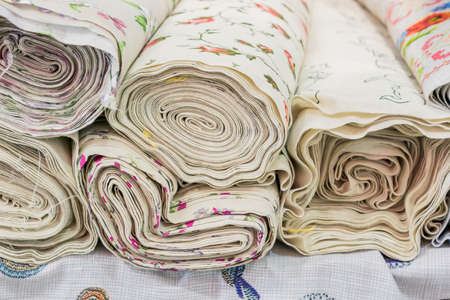 Rolls of natural fabrics and textiles lie at a market stand. Sewing industry concept