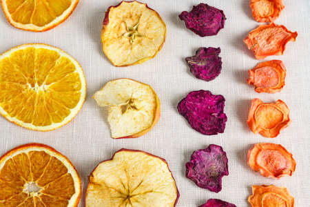 Healthy food organic nutrition. Sliced and dried apple, orange, carrot and beetroot in a row on textile background.の写真素材