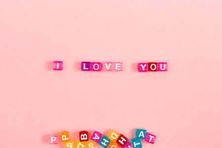 Love you inscription made of colorful cube beads with letters. Festive pink background concept with copy spaceの写真素材