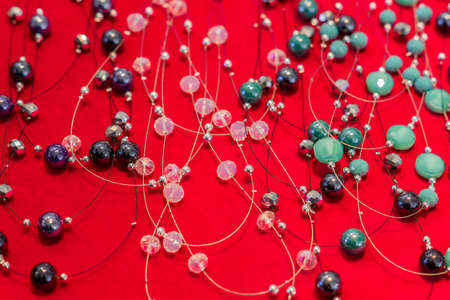 Colorful crystal beads necklaces on red background. Background pattern. Handicraft fashionable for womenの写真素材