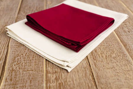 close up of cloth napkins of beige, and burgundy colors on rustic brown wooden table. Shallow depth of field.の写真素材