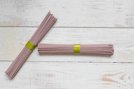 Raw soba noodle on whte wooden table. Traditional Japanese food. Top view, copy space