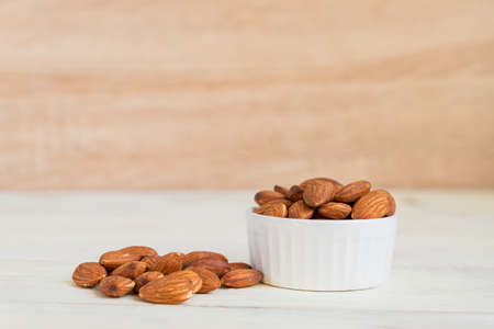 Pile of Roasted Almonds on white wooden table, close up, copy spaceの写真素材