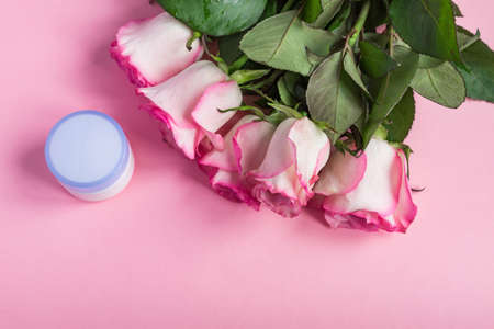 Pink blooming roses and face cream on pastel pink background. Romantic skincare floral frame. Copy spaceの写真素材