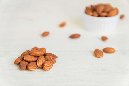 Pile of Roasted Almonds on white wooden table, close up, copy spaceの写真素材
