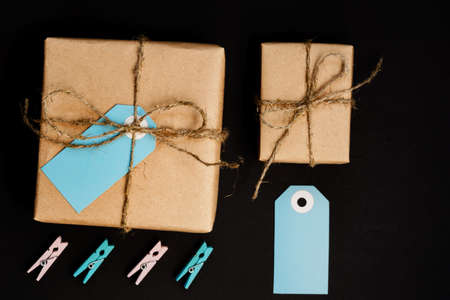 Handcrafted gift boxes wrapped in Craft paper with blue paper card tag, rope and wooden clothespins for decoration.の写真素材