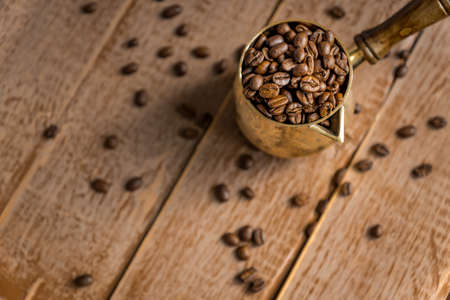 Close up of fresh roasted coffe beans in cezve (traditional turkish coffee pot) on wooden table.の写真素材