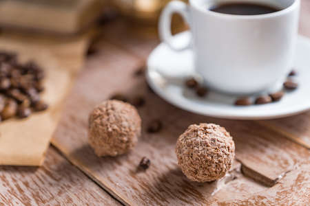 Coffee time break. Cup of freshly breved turk coffee, chocolate balls and book on wooden tableの写真素材