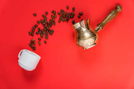 Top view of coffe beans in cezve (traditional turkish coffee pot), whte cup on red background.の写真素材