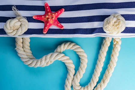 Sea shells, starfish and textile stiped navy bag with rope knots on light blue background. summer holiday and vacation conceptの写真素材