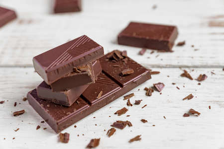 Chocolate bars on wooden table. Broken pieces of dark chocolate. Food background