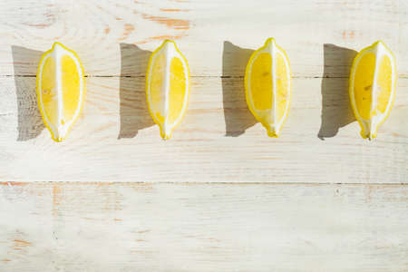 top view of quarter lemons on wooden table. Hard shadows in a saunny dayの写真素材