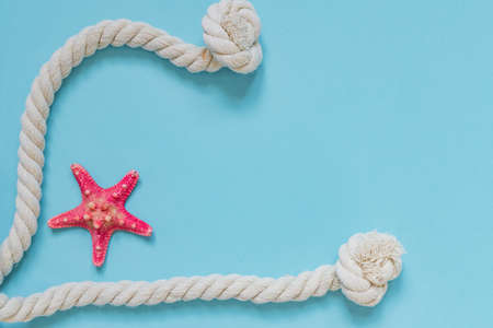 Red starfish and knot rope on light blue background with copy space. summer holiday and vacation conceptの写真素材