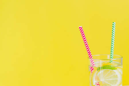 Homemade lemonade with lemon and mint on colored yellow background. Summer cold drink cocktail. Copyspaceの写真素材